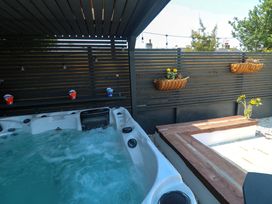 A hot tub with a wooden bench and flower pots at Carn Brea in Redruth