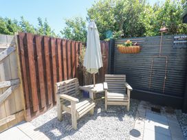A garden with wooden chairs and a table under an umbrella at Carn Brea in Redruth