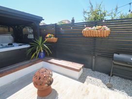 An outdoor area with a hot tub, bench, and grill at Carn Brea in Redruth