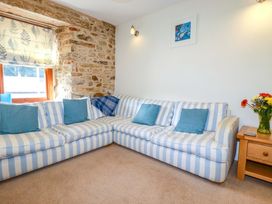 A living room with a striped sofa and a vase of flowers at 3 The Old Cornstore