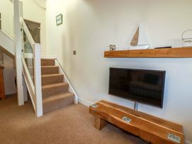 A hallway with stairs and a television on a wooden bench at 3 The Old Cornstore