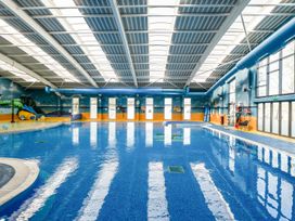 An indoor pool with a water slide and lifeguard chair at Nature's Nook - Billing Aquadrome