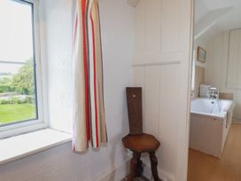 A bathroom with a window, curtain, stool and bathtub at Trevean in Bude