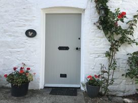 A grey door with flowers and a nameplate at Trevean in Crackington Haven