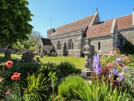 An outdoor view of a church with flowers and a statue at Mallow Cottage in Langton Matravers