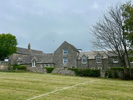 A stone house with grass and trees at Mallow Cottage in Langton Matravers