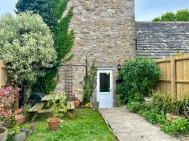 A garden with a stone wall and plants at Mallow Cottage in Langton Matravers