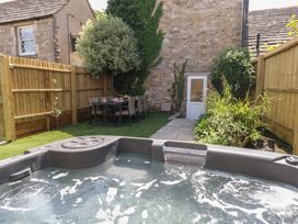 A garden with a hot tub and dining table at Mallow Cottage in Langton Matravers