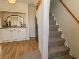 A hallway with a staircase and sideboard at Mallow Cottage in Langton Matravers