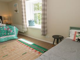 A bedroom with a bed, lamp, and window at Mallow Cottage in Langton Matravers