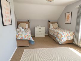 A bedroom with two beds and a dresser at Mallow Cottage in Langton Matravers