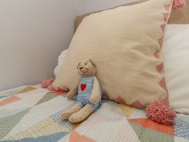 A bed with a pillow and a toy bear at Mallow Cottage in Langton Matravers