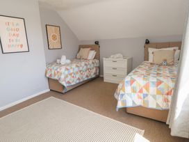A bedroom with two beds and a dresser at Mallow Cottage in Langton Matravers
