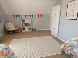 A bedroom with a bookshelf and a bear stuffed toy at Mallow Cottage in Langton Matravers
