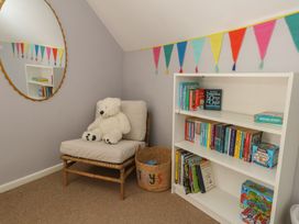 A reading room with a chair and bookshelves at Mallow Cottage in Langton Matravers