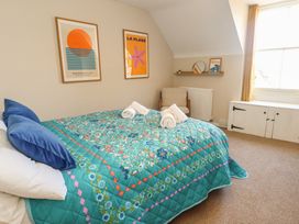 A bedroom with a bed and artwork on the wall at Mallow Cottage in Langton Matravers