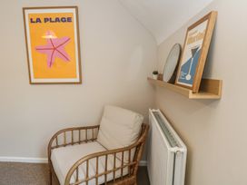 A seating area with a chair and shelf featuring decor at Mallow Cottage in Langton Matravers