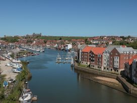 A marina with boats and buildings along the river at The Shipwrights in Whitby