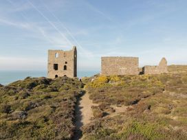 Ruins on a hillside with vegetation and a pathway at Chy Vean in St. Agnes