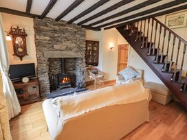 A living room with a stone fireplace and stairs at Stoker’s Cottage in Windermere