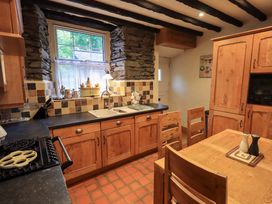 A kitchen with wooden cabinets and a dining table at Stoker’s Cottage in Windermere