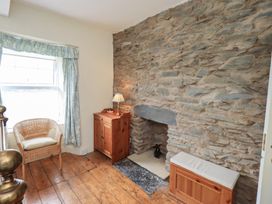 A sitting room with a stone wall and a wicker chair at Stoker’s Cottage in Bowness-On-Windermere