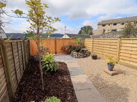 A garden with a tree and gravel path at Stoker’s Cottage Bowness-On-Windermere