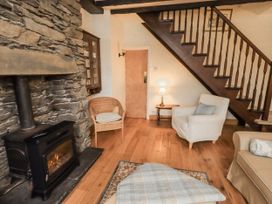 A living room with a fireplace and wooden stairs at Stoker’s Cottage in Bowness-On-Windermere