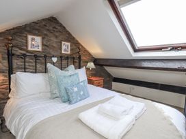 A bedroom with a bed and decorative pillows at Stoker’s Cottage, Bowness-On-Windermere