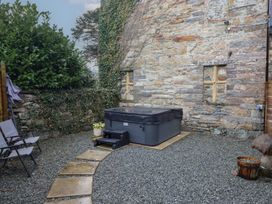 A garden with a hot tub and stone wall at Idris Barn Dolgellau
