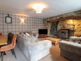 A living room with a sofa, dining table and fireplace at Cader Cottage in Dolgellau