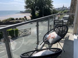 A balcony with chairs and a table overlooking the ocean at 10 Croft Court in Tenby
