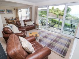 A living room with leather sofas and a view of the balcony at Lifeboat Lookout in Tenby