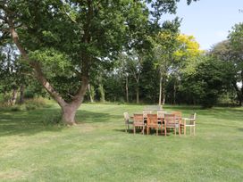 An outdoor area with a table and chairs under a tree at 1 The Stables, Highbridge