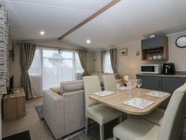 A living room with a dining area and kitchen appliances at Woodland Way in Benllech