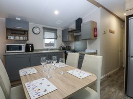 A kitchen with a table and chairs at Woodland Way in Benllech