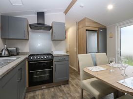 A kitchen with appliances and dining table at Woodland Way in Benllech