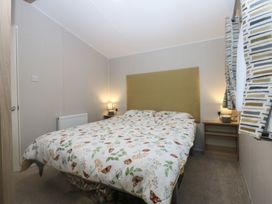 A bedroom with a bed and nightstand at Woodland Way in Benllech