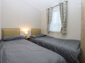 A bedroom with two single beds and a lamp at Woodland Way in Benllech