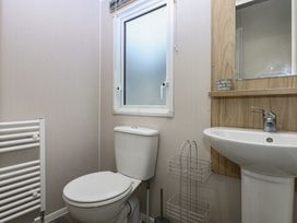 A bathroom with a toilet, sink and window at Woodland Way in Benllech