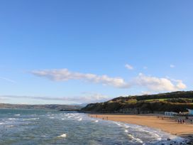 A beach with people walking along the shoreline at Woodland Way in Benllech