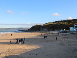 A beach with people walking and a cafe at Woodland Way in Benllech
