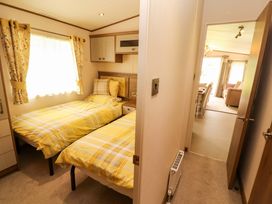 A bedroom with two beds and curtains at 22 Yealand in Carnforth