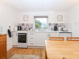 A kitchen with an oven, sink, and table at Hafan Bach in Bwlchtocyn near Abersoch