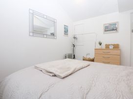 A bedroom with a bed and mirror at Hafan Bach in Bwlchtocyn near Abersoch