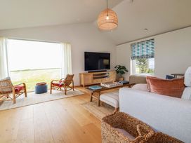 A living room with a television and two rattan chairs at 8 Karn Havos St. Eval near Mawgan Porth