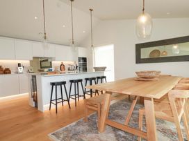 A kitchen with a dining table and bar stools at 8 Karn Havos St. Eval near Mawgan Porth