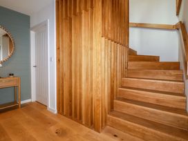 A hallway with wooden stairs and a wall mirror at 8 Karn Havos St. Eval near Mawgan Porth