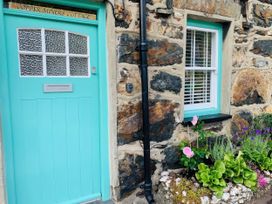 A door and window with a flowerbed at Copper Miners Cottage in Beddgelert, Eryri (snowdonia)