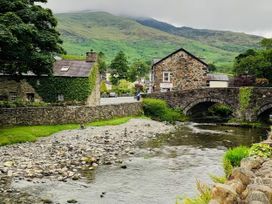 A view of houses and a bridge over a river near mountains at Copper Miners Cottage Beddgelert, Eryri (snowdonia)